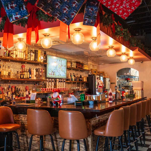 Polanco Taqueria's festive bar area with bottles, brown stools, and Christmas decorations.