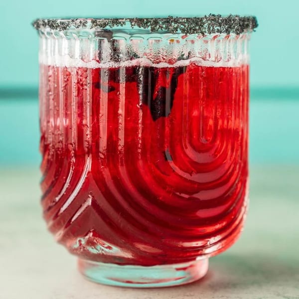 A vibrant red Polanco Taqueria drink in a textured glass with a dark, salted rim.