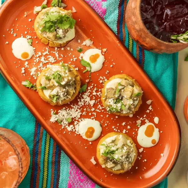 Polanco Taqueria's sopes with chicken, cheese, and cilantro on an orange platter with sauce.